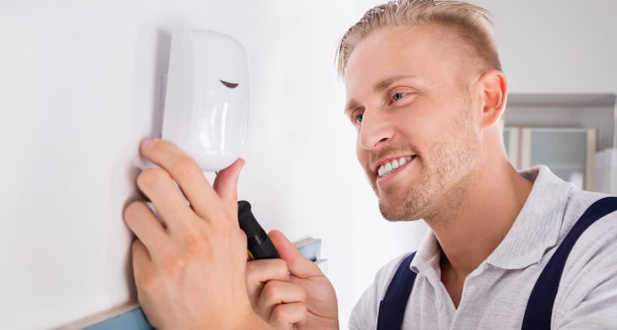 Man placing a motion detector in a living area